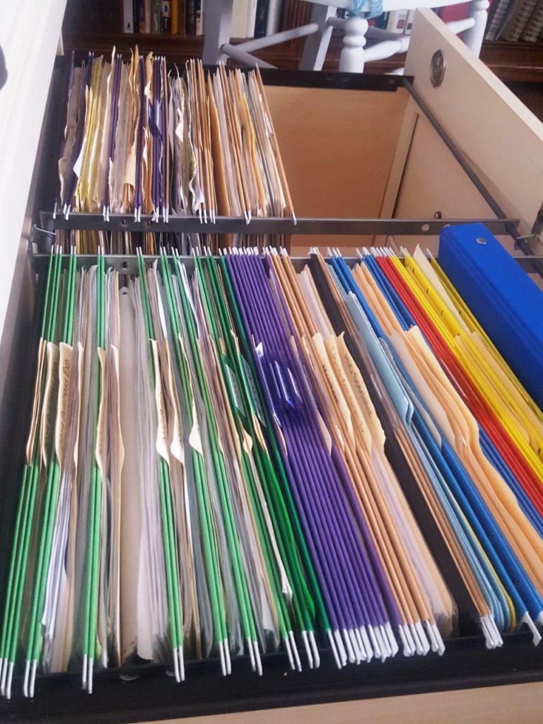 two-drawer file cabinet with color-coded files where one drawer is now half-empty